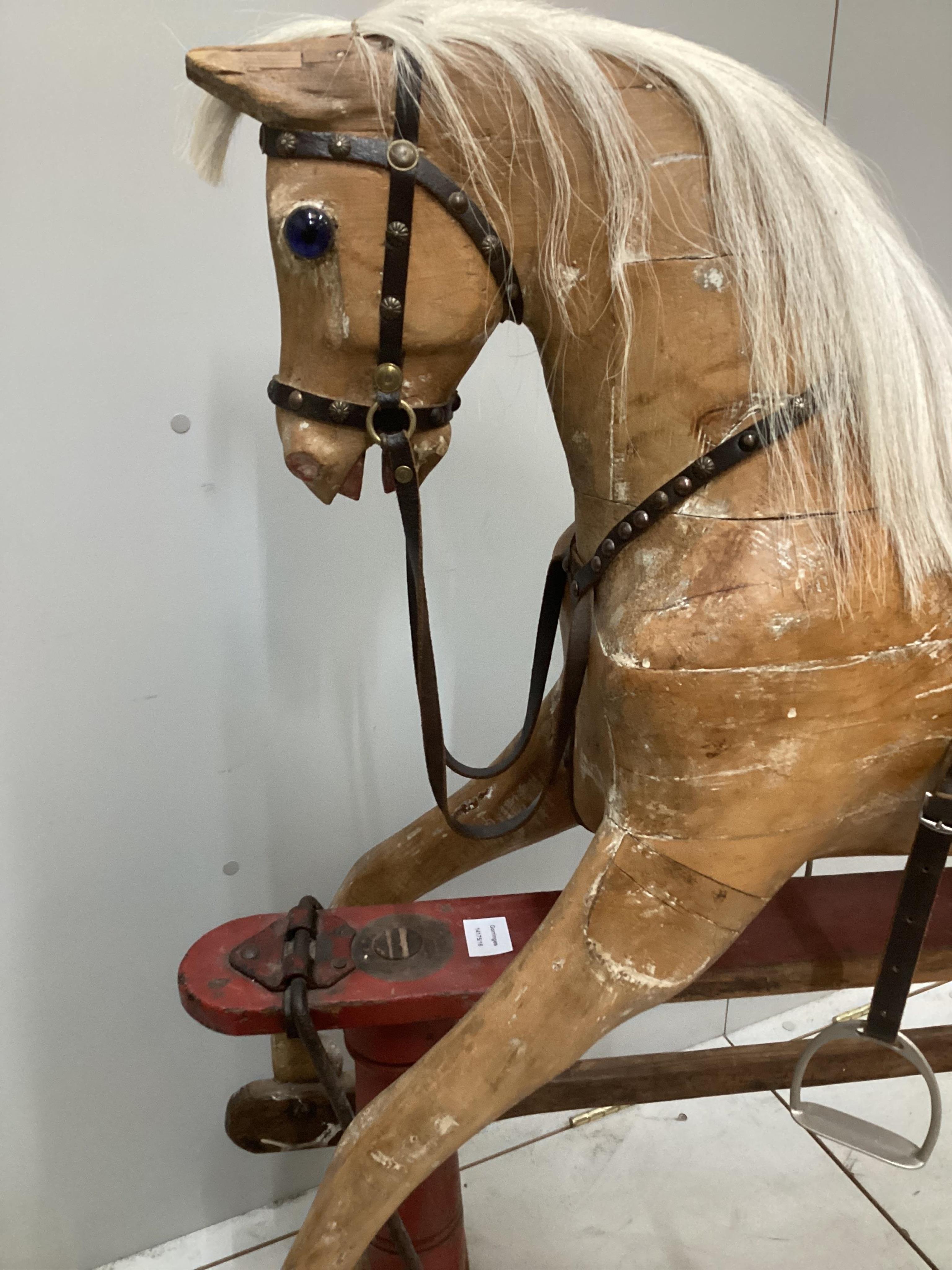 An early 20th century carved wood rocking horse on stand (a.f.), 117cm high, base of stand 146 wide